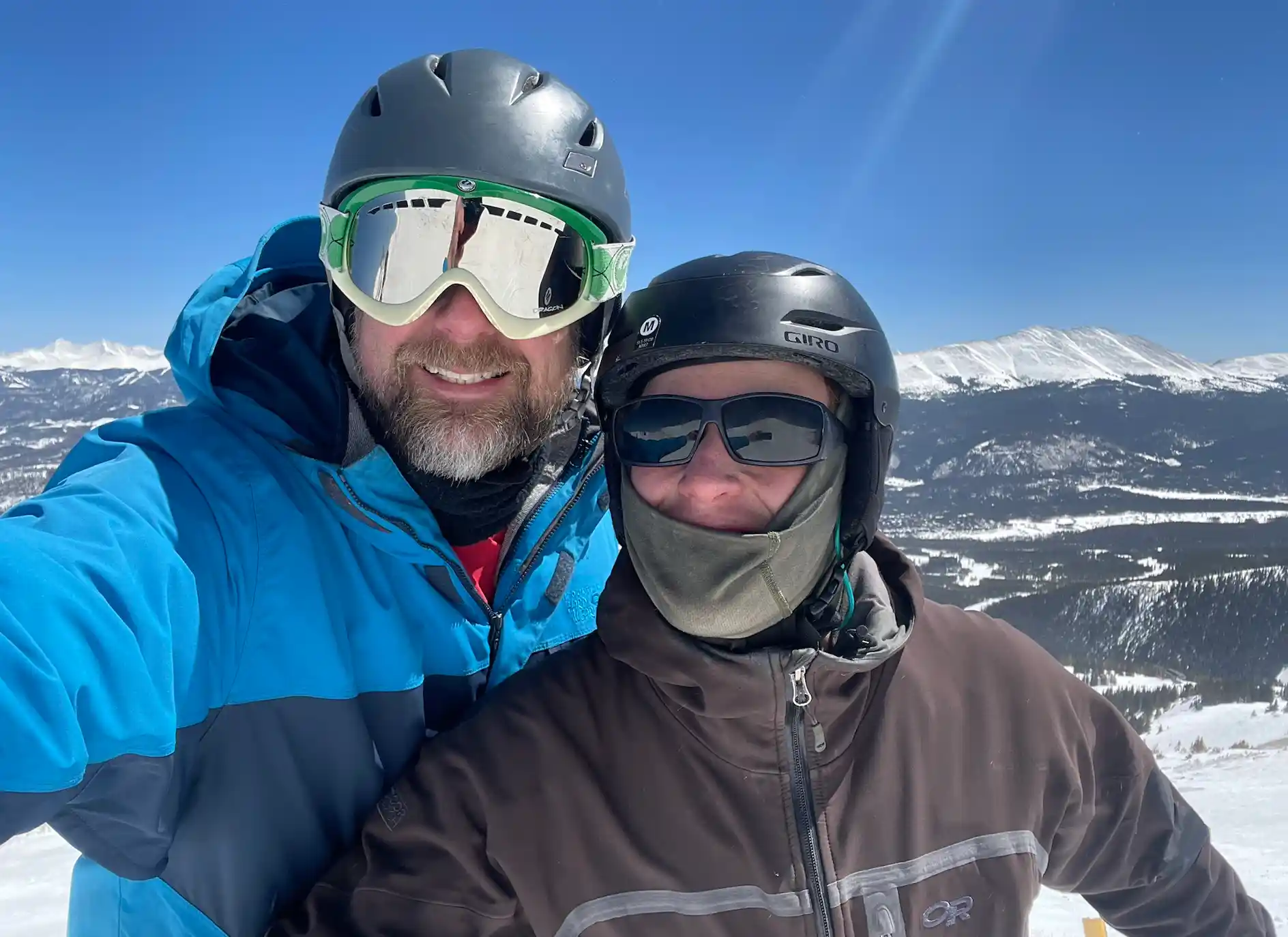 Two men with skiing gear standing in front of a mountain